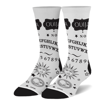 White crew socks with a black Ouija board design, featuring the alphabet, numbers, stars, and vintage sun and moon faces.