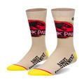 Pair of beige crew socks with a Jurassic Park logo and 'Asset Containment' text. Yellow accents at the toe and heel.