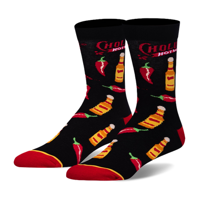 Black crew socks featuring a pattern of Cholula hot sauce bottles, red chili peppers, the Cholula logo, and red toe accents.