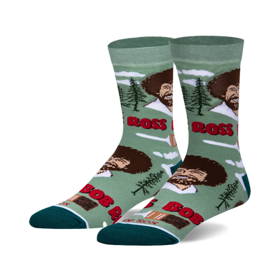 Crew socks in teal green and white featuring Bob Ross's smiling face, paintbrushes, and happy little trees. 
