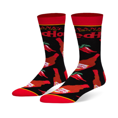 Black crew socks featuring a pattern of Frank's RedHot sauce bottles and red chili peppers, with a bright red toe and cuff.