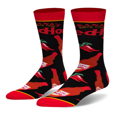 Black crew socks featuring a pattern of Frank's RedHot sauce bottles and red chili peppers, with a bright red toe and cuff.