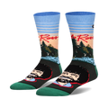 Pair of crew socks featuring Bob Ross's portrait and a sunset landscape.  Colors include teal, light blue, orange, and dark green.