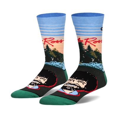Pair of crew socks featuring Bob Ross's portrait and a sunset landscape.  Colors include teal, light blue, orange, and dark green.
