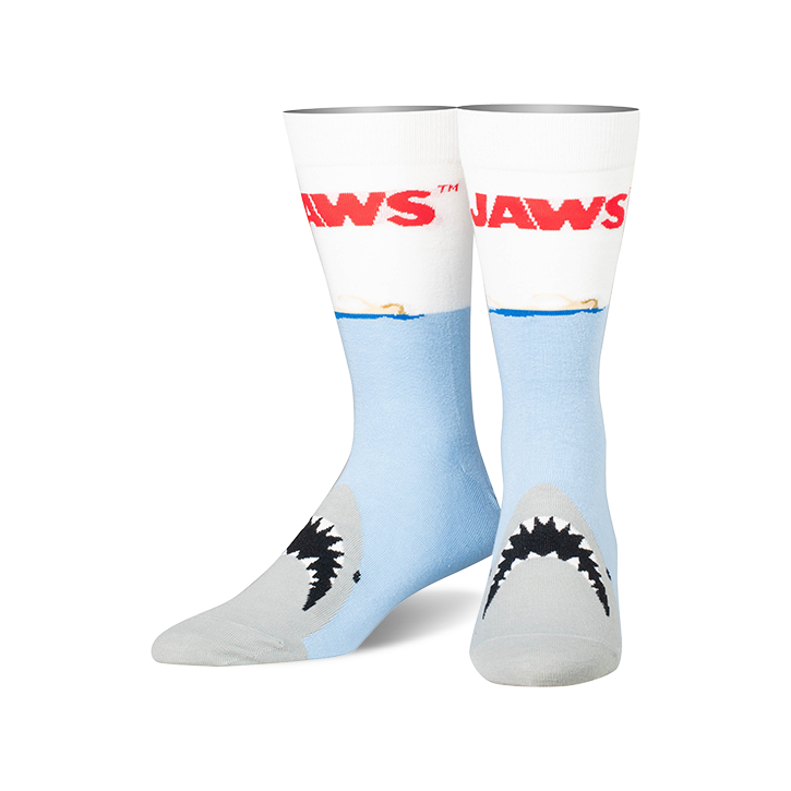 A pair of crew socks, predominantly light blue and white, feature the 'JAWS' title and a shark's mouth emerging from the water.