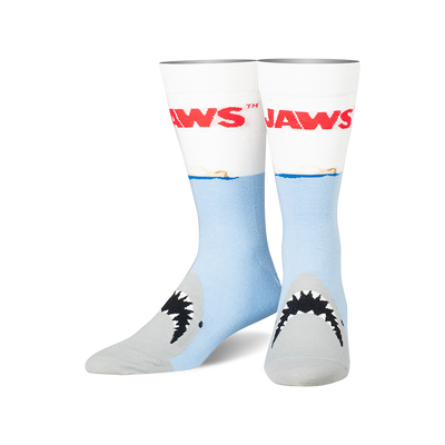 Crew socks, light blue with white cuffs, featuring the red Jaws logo, a blue ocean line, and a grey shark's mouth with teeth.