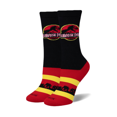 Pair of crew socks in black, red, and yellow. Feature Jurassic Park logo and black tree silhouettes.