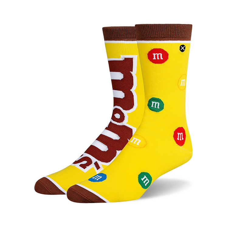 Crew socks in yellow with brown cuffs, featuring the M&Ms logo and multicolored M&Ms candies scattered across the design.