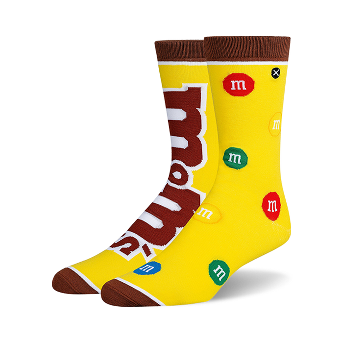 Crew socks in yellow with brown cuffs, featuring the M&Ms logo and multicolored M&Ms candies scattered across the design.