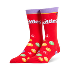 Bright red crew socks featuring a purple cuff, the white Skittles logo, and scattered colorful candy pieces with white S marks.