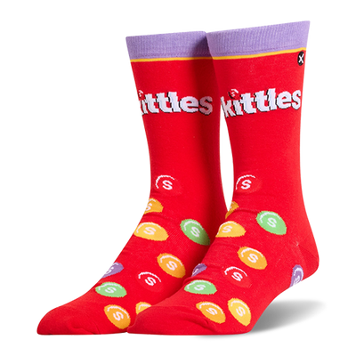 Bright red crew socks featuring a purple cuff, the white Skittles logo, and scattered colorful candy pieces with white S marks.