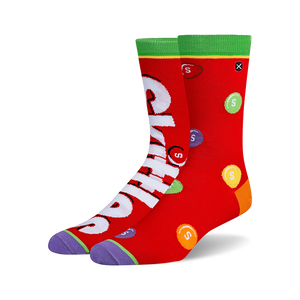 Pair of crew socks, predominantly red, featuring a Skittles design with the Skittles logo and multicolored candies printed on them.