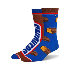 Pair of crew socks; one sock shows a Snickers bar graphic, the other has scattered Snickers pieces on a blue background. Brown and blue are the main colors.