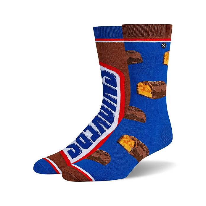 Pair of crew socks; one sock shows a Snickers bar graphic, the other has scattered Snickers pieces on a blue background. Brown and blue are the main colors.