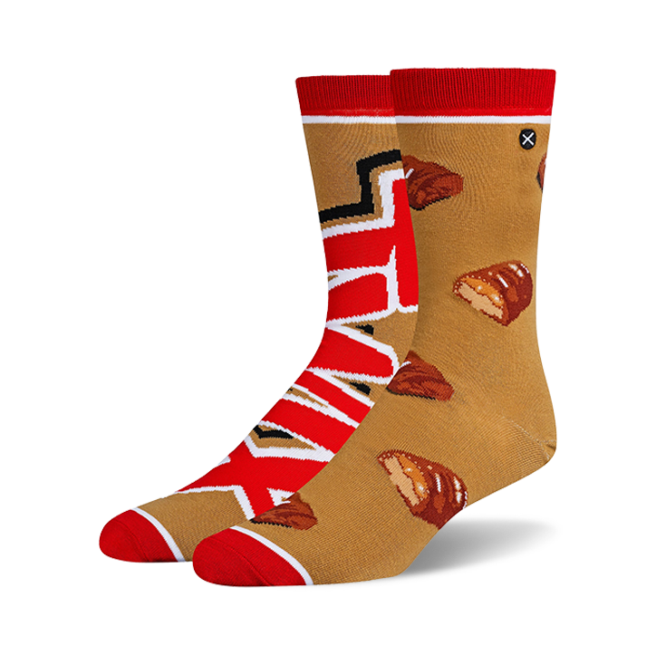 Pair of crew socks in tan and red. One sock features the Twix logo, the other has scattered Twix bar images.
