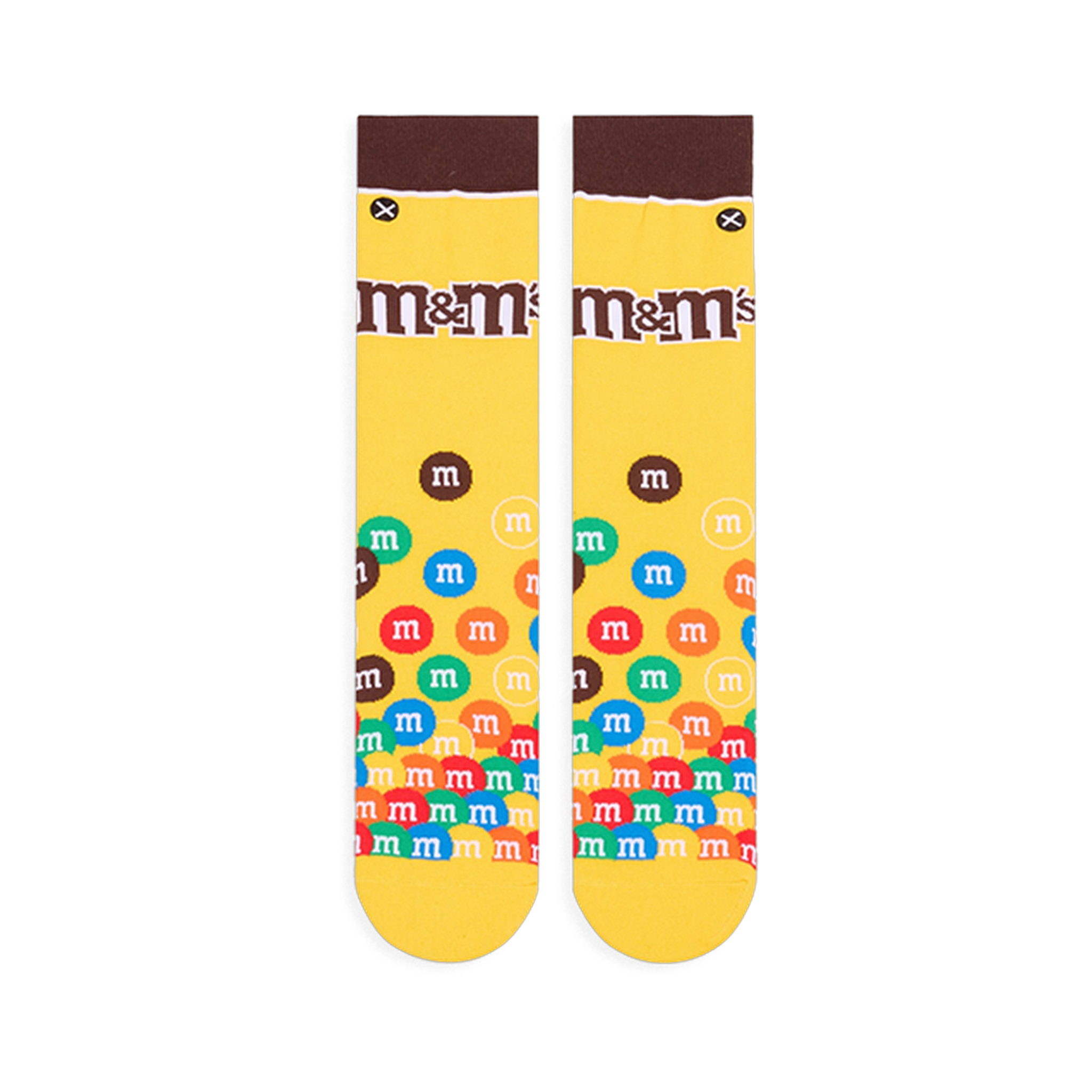 Flat lay of yellow crew socks showing a brown cuff, the M&M's logo on the calf, and colorful M&M candies piled at the toe.