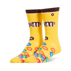 Bright yellow crew socks featuring a brown cuff, the M&M's logo on the leg, and a colorful pile of M&M candies on the foot.