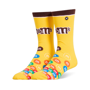 Bright yellow crew socks featuring a brown cuff, the M&M's logo on the leg, and a colorful pile of M&M candies on the foot.
