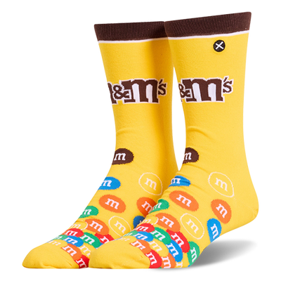 Bright yellow crew socks featuring a brown cuff, the M&M's logo on the leg, and a colorful pile of M&M candies on the foot.