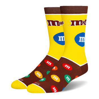 Yellow and brown M&M's crew socks with the classic logo on the leg and a pattern of colorful candy pieces on the dark foot.