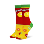 Crew socks with a red upper featuring the Skittles logo, green cuffs and heels, and a yellow foot with scattered candy pieces.
