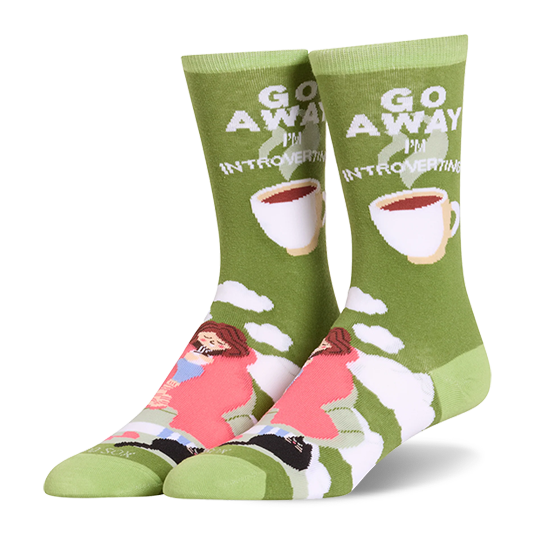 Olive green crew socks showing a person in a pink blanket, a black cat, coffee cups, and Go Away I'm Introverting text.