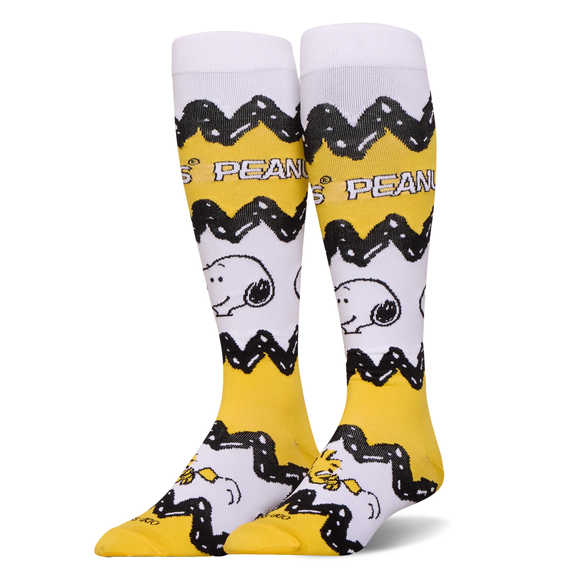 Tall yellow and white Peanuts socks featuring Charlie Brown's black zigzag pattern, Snoopy's face, and Woodstock at the toe.