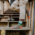 Vertical shot of a person climbing rustic wooden stairs, the bison graphic on Yellowstone National Park socks in Brown Heather front and center. [lf]