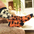 Lifestyle shot of Palm Socks in orange and black on a person relaxing outdoors. [lf]
