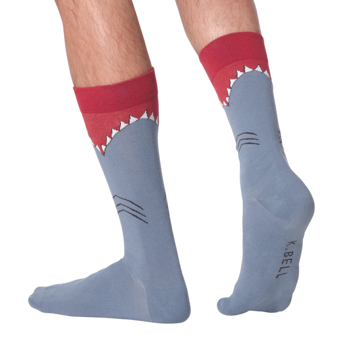 A pair of blue socks with a shark face on each sock. The shark has a red fin and black eyes.