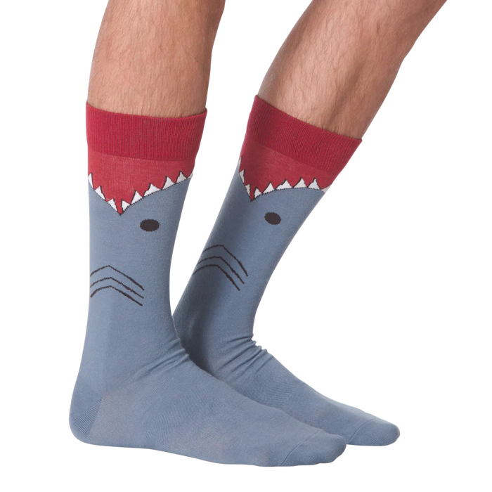 A pair of blue socks with a shark face on each sock. The shark has a red fin and black eyes.