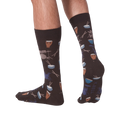 Lifestyle shot showing the 'Drums' socks on a person's legs from the back. The socks are dark brown with a drum set pattern.