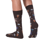 Lifestyle shot showing the 'Drums' socks on a person's legs from the back. The socks are dark brown with a drum set pattern.