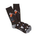 A pair of black crew socks with a golfer design.  The golfer is orange and teal, with golf balls and clubs scattered on the foot.