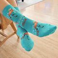 Lifestyle shot of model's legs wearing 'I Don't Give a Flock' socks while seated on a chair.