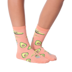 Lifestyle shot of woman's legs wearing peach avocado socks, different pose.