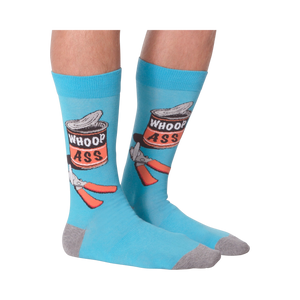 Flat lay photo of a pair of 'Whoop Ass' socks on a black background.