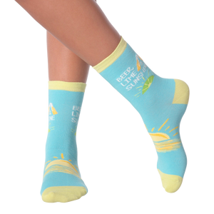 A person is sitting with their feet on a table. They are wearing blue socks with a pattern of lemons and the text 