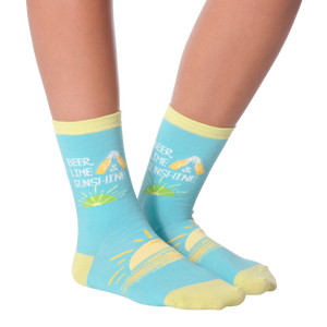 A person is sitting with their feet on a table. They are wearing blue socks with a pattern of lemons and the text 