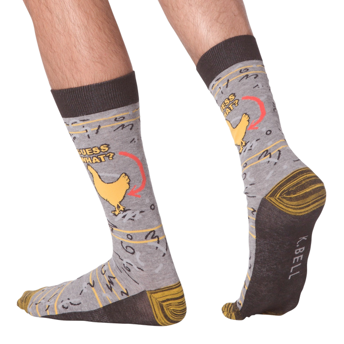 A pair of gray socks with a brown cuff. The socks have a pattern of chickens on them. The chicken has an arrow pointing to it with the words 