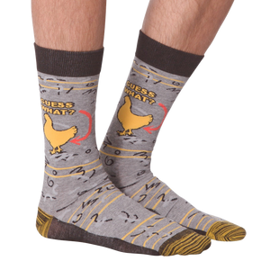 A pair of gray socks with a brown cuff. The socks have a pattern of chickens on them. The chicken has an arrow pointing to it with the words 