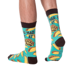 Lifestyle photo showing the 'You Had Me at Tacos' socks on a person's feet. The teal and yellow sock pattern is visible.
