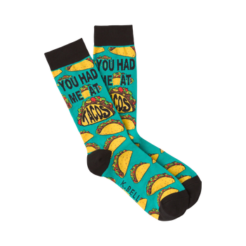 Pair of teal crew socks with a repeating pattern of tacos and the phrase 'You Had Me at Tacos.'  Black cuff.