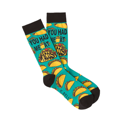 Pair of teal crew socks with a repeating pattern of tacos and the phrase 'You Had Me at Tacos.'  Black cuff.