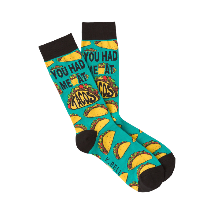 Pair of teal crew socks with a repeating pattern of tacos and the phrase 'You Had Me at Tacos.'  Black cuff.