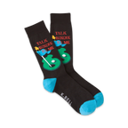 Pair of black crew socks with a golf-themed design. Features a putting green, golf ball, flags, and the text 'Talk Birdie To Me'. Teal blue cuffs.