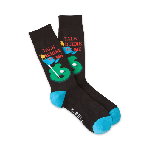 Pair of black crew socks with a golf-themed design. Features a putting green, golf ball, flags, and the text 'Talk Birdie To Me'. Teal blue cuffs.