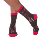 Lifestyle shot of model's legs wearing the 'Fifty Sips of Red' socks, showing the socks on feet.