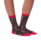 Another lifestyle shot showcasing the 'Fifty Sips of Red' socks on a model's legs from a slightly different angle.