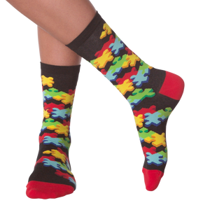 A pair of black socks with a colorful puzzle pattern. The socks have red toes and heels.